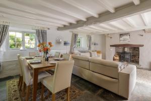 een woonkamer met een grote bank en een tafel bij Putsborough Manor 3 Self Catering Cottages with Beach a short walk, dog friendly all year, On site Tennis, Play Area, Paddock, Spa baths, BBQ, Private Gardens, Superfast WIFI in Croyde