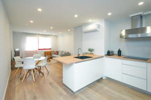 a kitchen with white cabinets and a table and chairs at URBANIZACION CON PISCINA ARNELAS SANXENXO in Sanxenxo