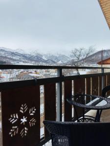 einen Balkon mit einem Tisch und Blick auf die schneebedeckten Berge in der Unterkunft Villa B Barleon-Bakuriani in Bakuriani