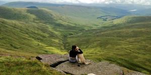 a woman sitting on a rock on a mountain at Attenborough Cottage - 2 Bedroom Cottage in Tredegar