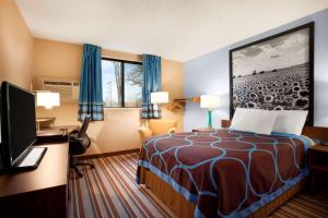 a hotel room with a bed and a desk and a television at Super 8 by Wyndham Pittsburg KS in Pittsburg