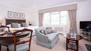 a bedroom with a bed and a living room with a table at Longueville Manor in Saint Helier Jersey