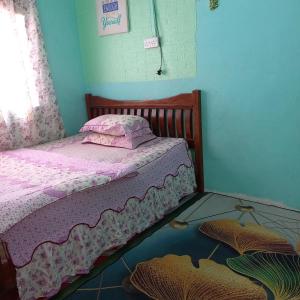 Dormitorio pequeño con cama con colcha rosa en Nur's Homestay en Seri Manjung