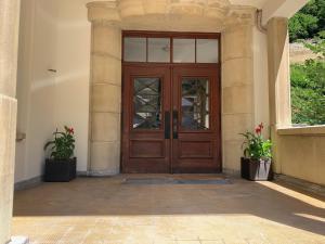 a wooden door in a building with two potted plants at Chambre Equipè à louer in Courrendlin