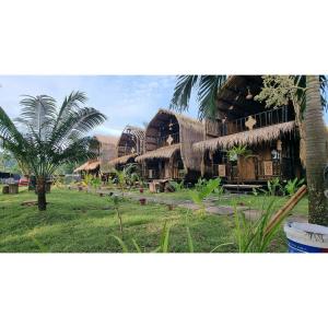 a resort with thatched roofs and a palm tree at Mahkota Atia Bungallow in Praya