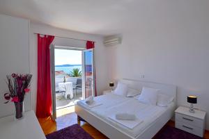 a white bedroom with a large bed and a balcony at Sunset apartments in Hvar