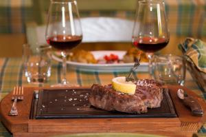 a steak on a plate with two glasses of wine at Al Giumani in Mammola +24 photos