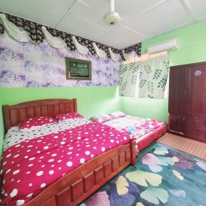 a bedroom with a bed with pink polka dots at Nur's Homestay in Seri Manjung