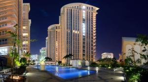 un grand bâtiment avec une piscine devant dans l'établissement Venice Luxury Residences, à Manille