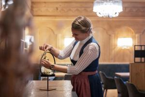 a woman is standing at a table with a clock at Hotel Stubaierhof in Neustift im Stubaital +253 photos