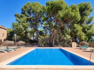 a swimming pool with trees in the background at Masía de San Juan Casas Rurales con piscina, aire acondicionado y vistas a la montaña in Segorbe