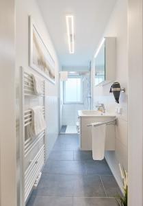ein weißes Badezimmer mit einem Waschbecken und einem Spiegel in der Unterkunft Nordseestern in Cuxhaven