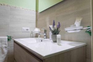 La salle de bains est pourvue d'un lavabo et d'un vase de fleurs violettes. dans l'établissement Appartamento a 200 metri dal mare Granseola, à Alghero