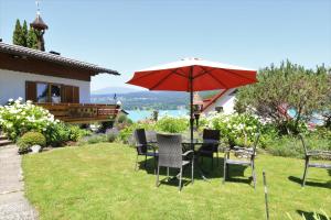 a table and chairs with an umbrella in the grass at Ferienwohnung Schellander Privatstrand in Velden am Wörthersee