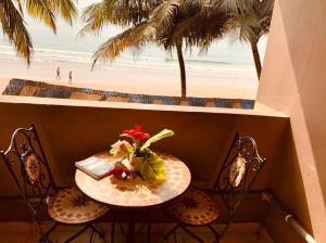 a table with a book and a vase of flowers on top of a beach at Kangaroo Pouch Beach Resort in Busua