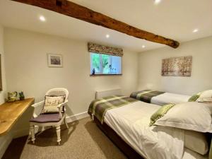 a bedroom with two beds and a desk and a chair at Stunning barn minutes from the Lake District in Penrith