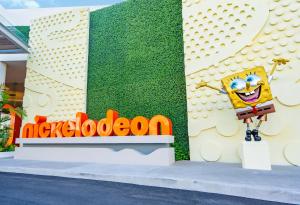 un personnage de bande dessinée de lego debout à côté d'un panneau à côté d'un bâtiment dans l'établissement Nickelodeon Hotels & Resorts Riviera Maya - Gourmet All Inclusive by Karisma, à Puerto Morelos