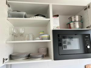 - une cuisine avec un four micro-ondes, des assiettes et des verres dans l'établissement Roosevelt Cosy 2BR Easy Access to Paris Free parking, à Saint-Germain-en-Laye