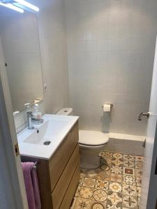 ein Badezimmer mit einem Waschbecken, einem WC und einem Spiegel in der Unterkunft Adosado cerca de la playa in Torredembarra
