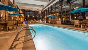a swimming pool with chairs and tables and umbrellas at Best Western Inn Tooele in Tooele