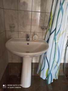 a white sink in a bathroom with a shower curtain at Sunny Room in Áyios Yeóryios