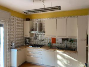 una cocina blanca con armarios blancos y fregadero en Villa Marie Claire en Ischia