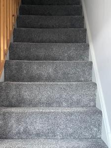 a staircase with grey carpeting and wooden steps at 27 The Limes Room 2 in Stockton on the forest