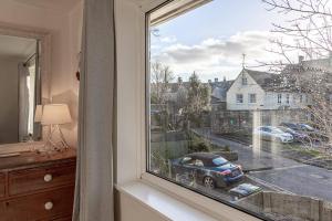 a window with a car parked on a street at Modern 2 BD w/ Garden in the Heart of Tetbury! in Tetbury