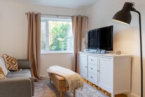 a living room with a television on a white dresser at Modern 2 BD w/ Garden in the Heart of Tetbury! in Tetbury