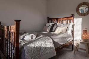 1 dormitorio con cama de madera y espejo en Modern 2 BD w/ Garden in the Heart of Tetbury!, en Tetbury