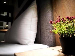 Una cama con una almohada y un jarrón de flores sobre una mesa en Insomnia studio Komotini en Komotini
