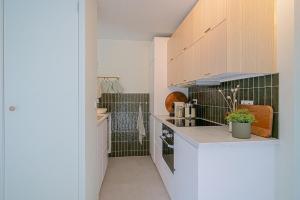 una cocina con armarios blancos y azulejos verdes en Diva in de Duinen - Park Duinland Sint Maartenszee, en Sint Maartensvlotbrug 17 fotos más