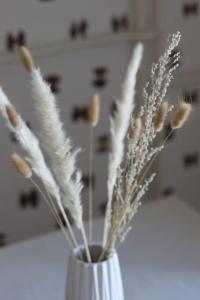 a white vase with some white flowers in it at City Center - TERRA Apartment in Pristina +14 photos