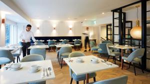 a man standing in a dining room with tables and chairs at Handel's Hotel in Dublin