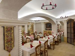 un comedor con mesas y sillas blancas y una lámpara de araña en Hotel Château Cihelny en Karlovy Vary