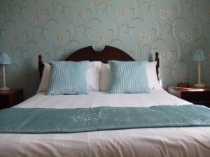 a bed with blue and white sheets and pillows at The Denewood in Sandown