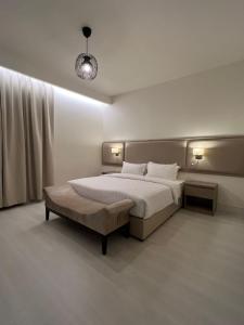 een slaapkamer met een groot bed en een lamp bij Ritaj Hotel Suites in Riyad