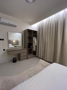 een slaapkamer met een bed en een televisie en gordijnen bij Ritaj Hotel Suites in Riyad