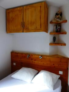a bedroom with a bed with a wooden headboard and cabinets at Appartements Confort Saint François Longchamp in Saint-François-Longchamp