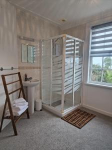 y baño con ducha acristalada y lavamanos. en Small Cottage close to Carbis Bay Beach & St Ives en Carbis Bay