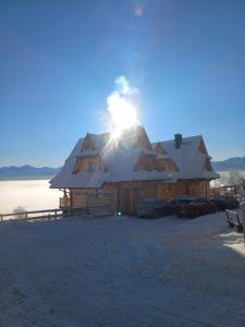 Cabaña de madera con techo cubierto de nieve en Domki Widokowe Panorama Tatr en Biały Dunajec