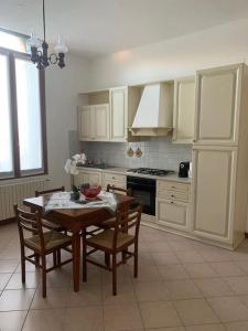 una cocina con mesa y sillas y una cocina con armarios blancos. en La casa di Anna - Palazzo Flantini, en Valdobbiadene