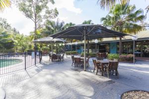 a patio with tables and chairs and an umbrella at NRMA Murramarang Beachfront Holiday Resort in Durras