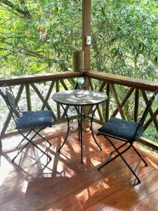 two chairs and a table on a wooden deck at Caoni riverside Lodge in Puerto Quito