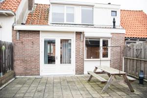 a wooden bench in front of a brick house at huisje de Strandjutter in Katwijk aan Zee