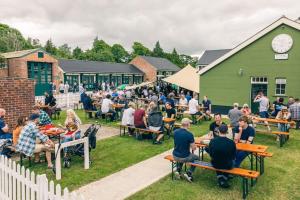 a crowd of people sitting at tables in front of a building at Duclos (Private Ensuite room) at Bicester Heritage in Bicester