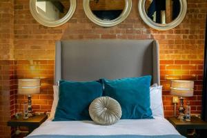 a bedroom with a bed with blue pillows and two mirrors at Duclos (Private Ensuite room) at Bicester Heritage in Bicester