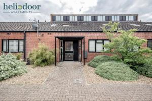 a brick house with a door and some bushes at HAML Heliodoor Apartments Milton Keynes, Free Parking, Free WiFi & Movies, 7-min drive to City Centre in Wolverton