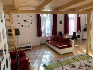 a living room with a couch and a clock on the wall at Város szíve apartman in Kaposvár