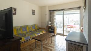 salon z kanapą i telewizorem w obiekcie Eleuthera- 174- Appart en rez de jardin- 4pers w Cap d'Agde
